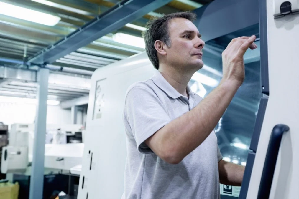 Engineer operates vertical CNC milling machine to produce precision machined components Engineer operates vertical CNC milling machine to produce precision machined components
