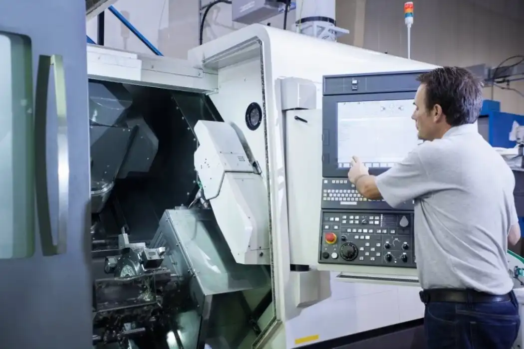 Operator sets parameters on CNC lathe machine for precision turning parts production