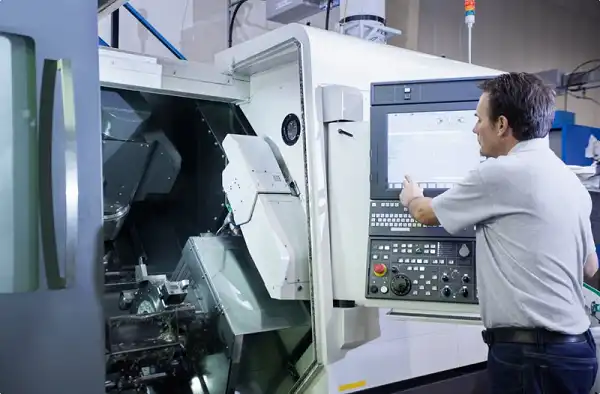Operator programming CNC lathe machine for precision turning of rotational components